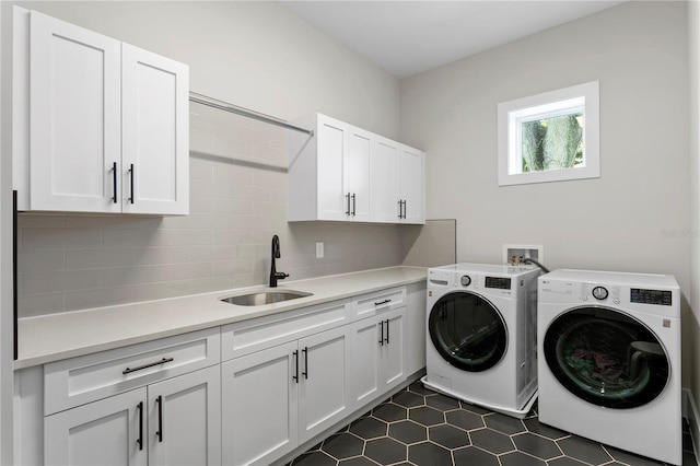 washroom featuring sink, washer and dryer, cabinets, and dark tile patterned floors