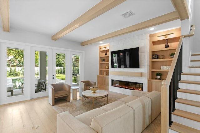 living room with french doors, beam ceiling, light wood-type flooring, and a fireplace