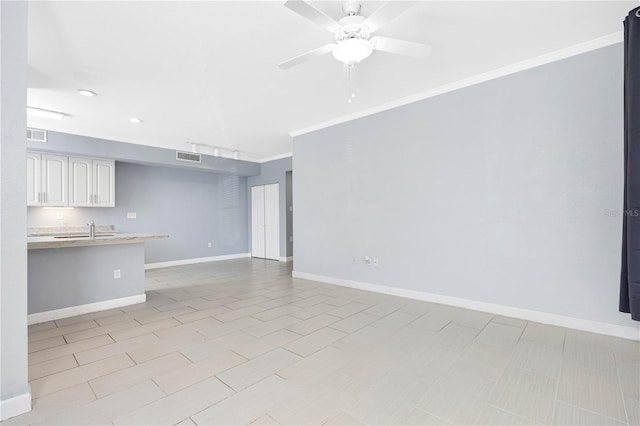 unfurnished living room featuring crown molding, sink, and ceiling fan