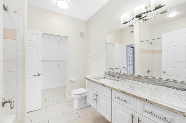 bathroom with vanity, tiled shower, toilet, and tile patterned floors