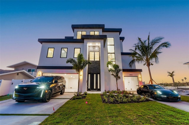 contemporary house featuring fence, concrete driveway, a garage, stucco siding, and a lawn