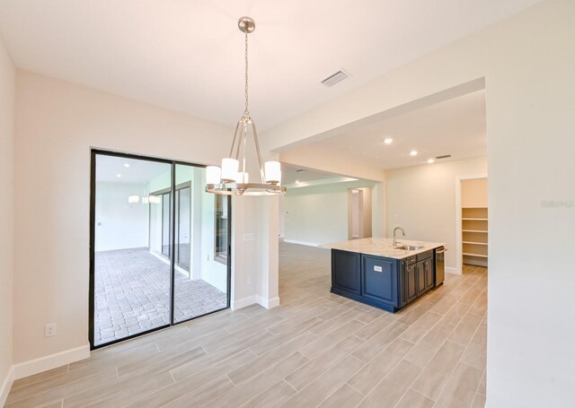 kitchen featuring pendant lighting, blue cabinetry, sink, and light wood-type flooring