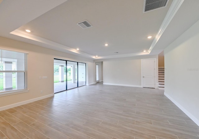 spare room featuring light hardwood / wood-style floors, a healthy amount of sunlight, and a tray ceiling