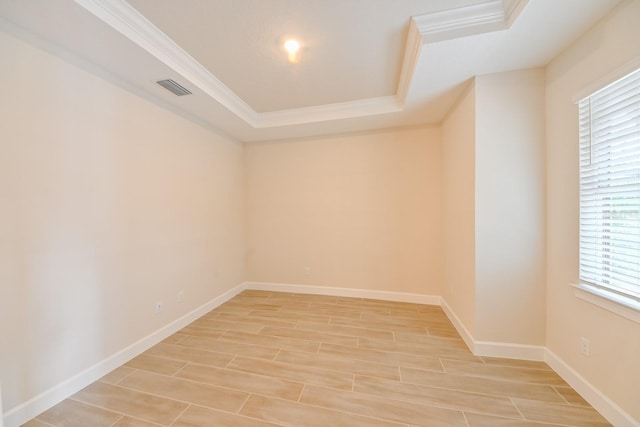 spare room featuring a tray ceiling, ornamental molding, and light hardwood / wood-style flooring