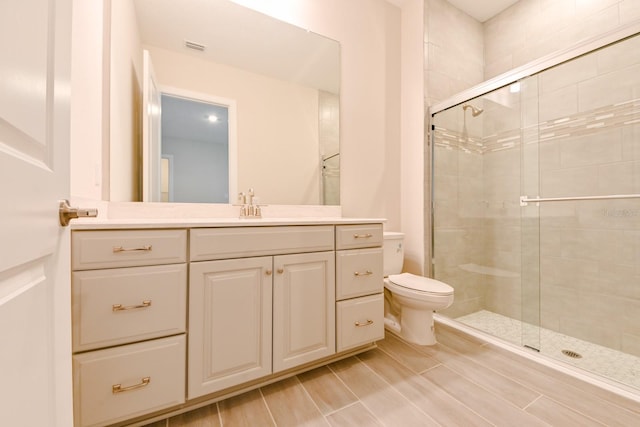 bathroom featuring vanity, toilet, and a shower with door