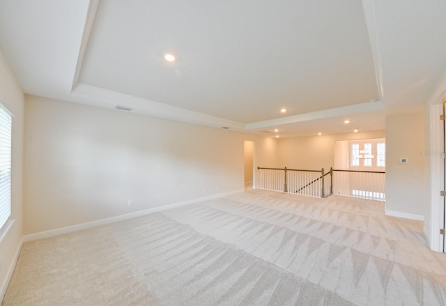 carpeted spare room featuring a tray ceiling