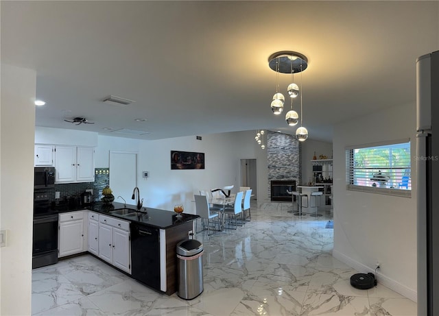 kitchen featuring white cabinets, backsplash, black appliances, a fireplace, and sink