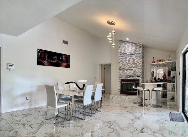 dining area with high vaulted ceiling and a stone fireplace