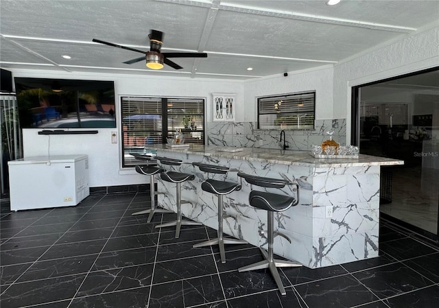 kitchen featuring refrigerator, a textured ceiling, light stone countertops, and ceiling fan