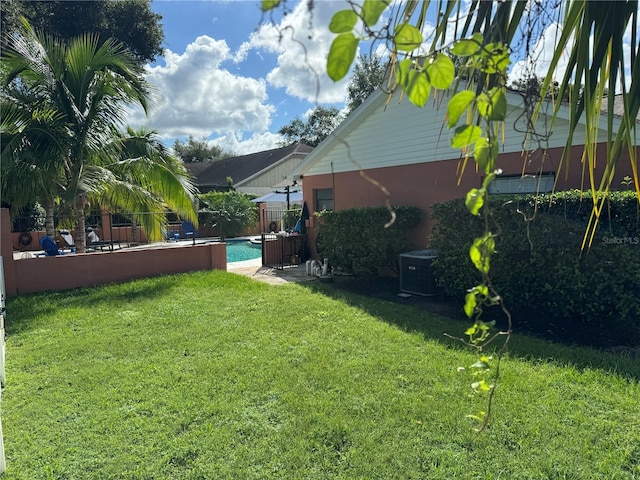 view of yard with central AC and a fenced in pool