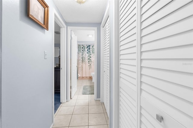 hallway featuring light tile patterned flooring and a textured ceiling