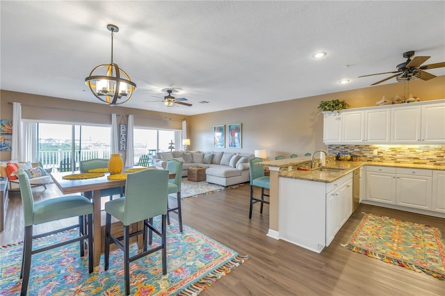 dining space featuring dark wood-type flooring, sink, and ceiling fan with notable chandelier