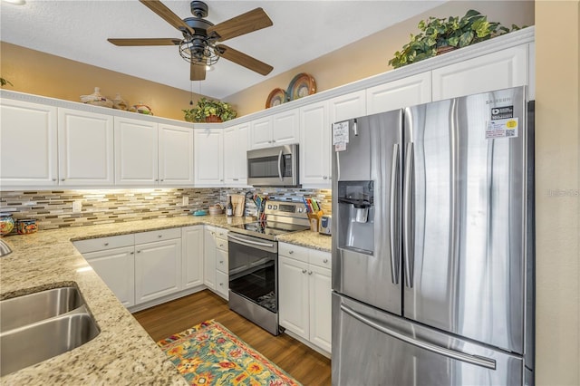 kitchen with sink, appliances with stainless steel finishes, light stone counters, and white cabinets