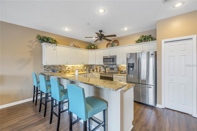 kitchen featuring kitchen peninsula, white cabinets, a textured ceiling, dark hardwood / wood-style floors, and stainless steel appliances