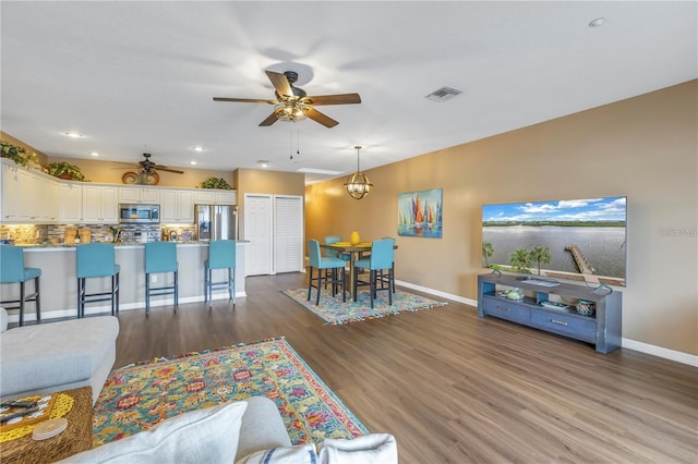 living room featuring hardwood / wood-style floors and ceiling fan with notable chandelier