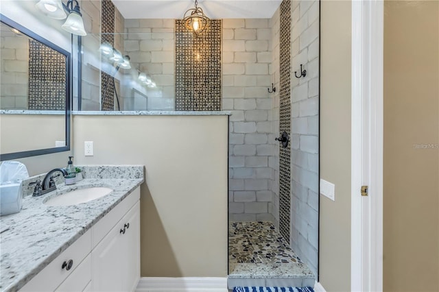 bathroom with a tile shower and vanity