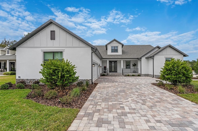 modern farmhouse featuring a front yard, a garage, and a porch