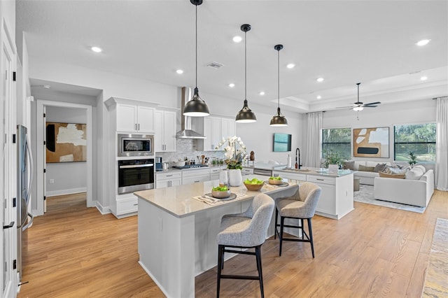 kitchen featuring a center island, white cabinets, a breakfast bar, light hardwood / wood-style flooring, and decorative light fixtures