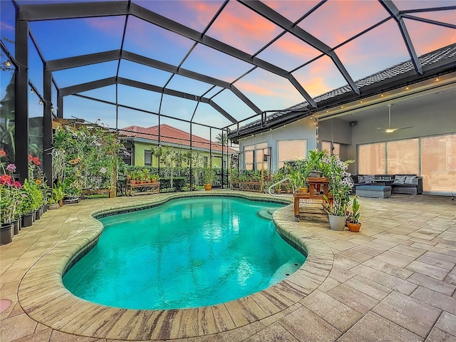 pool at dusk featuring a patio, an outdoor hangout area, and glass enclosure