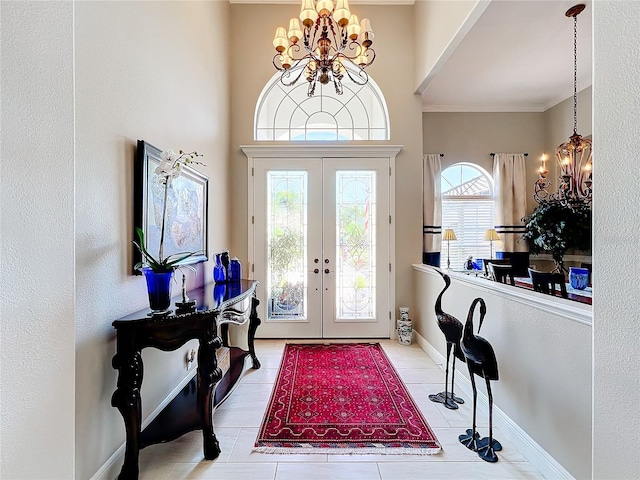 tiled foyer with ornamental molding, a chandelier, and french doors