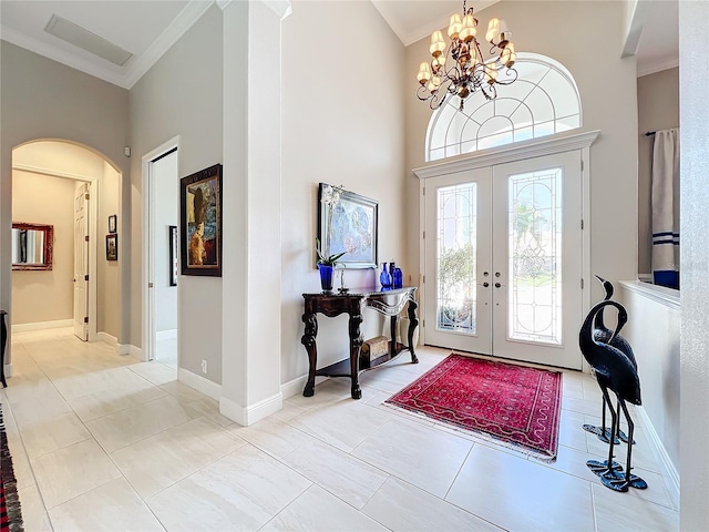 foyer with an inviting chandelier, french doors, a high ceiling, and crown molding