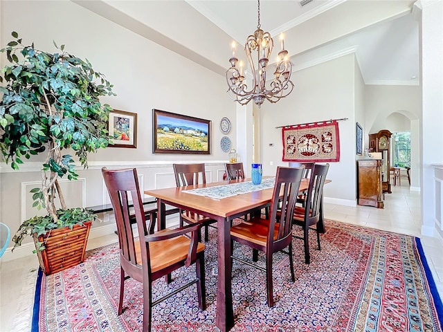 dining area with crown molding, a notable chandelier, a towering ceiling, and light tile patterned floors