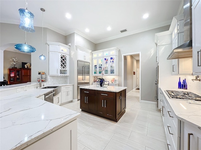 kitchen with appliances with stainless steel finishes, backsplash, hanging light fixtures, white cabinetry, and dark brown cabinetry