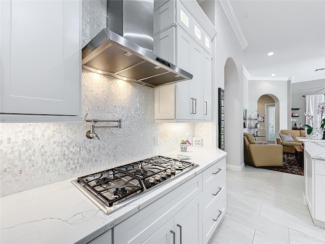 kitchen featuring light stone counters, stainless steel gas stovetop, and wall chimney range hood