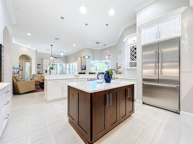 kitchen featuring stainless steel built in fridge, a center island, dark brown cabinetry, pendant lighting, and ceiling fan