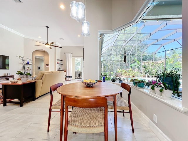 dining area featuring crown molding, ceiling fan, a high ceiling, and light tile patterned floors