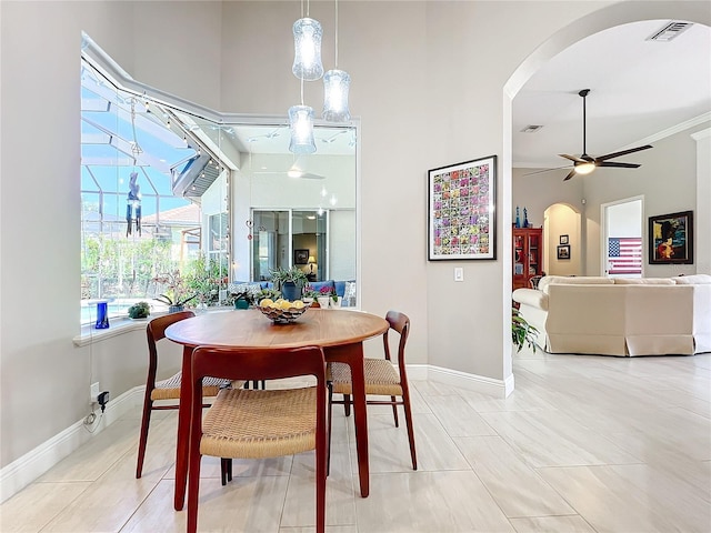 tiled dining area featuring ceiling fan and ornamental molding