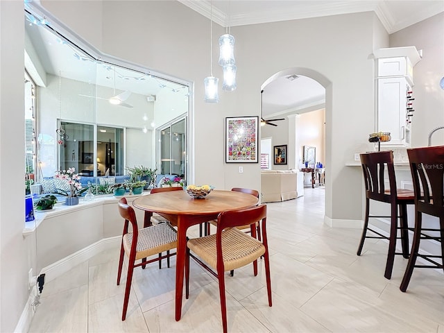 tiled dining space featuring ornamental molding, a high ceiling, and ceiling fan