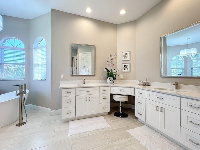 bathroom featuring vanity, a chandelier, and a bath