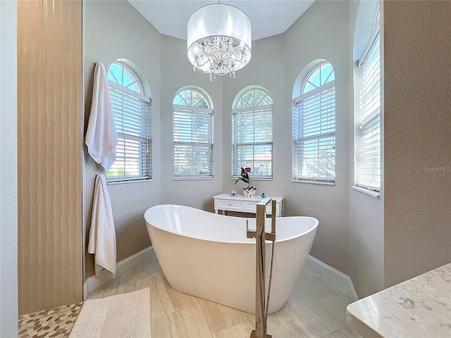 bathroom featuring a tub to relax in, a chandelier, and tile patterned flooring