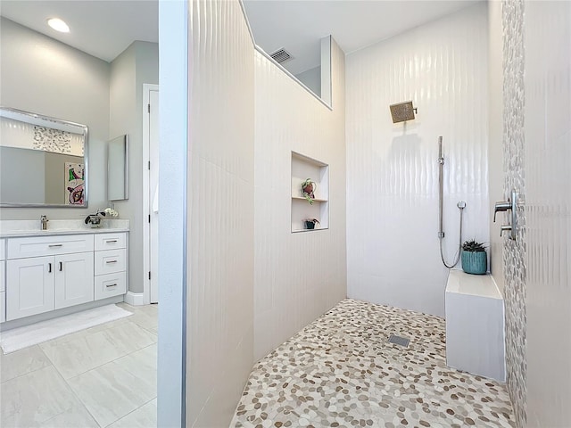 bathroom featuring a tile shower, vanity, and built in shelves