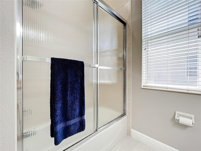 bathroom with tile patterned flooring and bath / shower combo with glass door