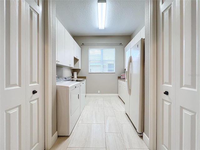 clothes washing area featuring a textured ceiling, cabinets, and washing machine and clothes dryer