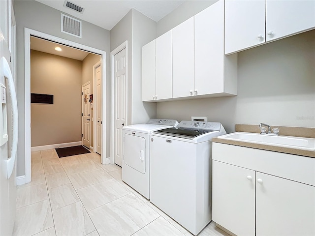 clothes washing area featuring sink, washing machine and dryer, and cabinets