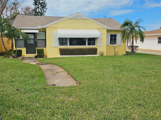 back of house featuring stucco siding, a shingled roof, and a yard