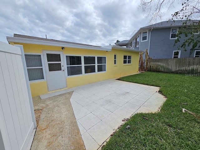 rear view of property with a patio and a lawn