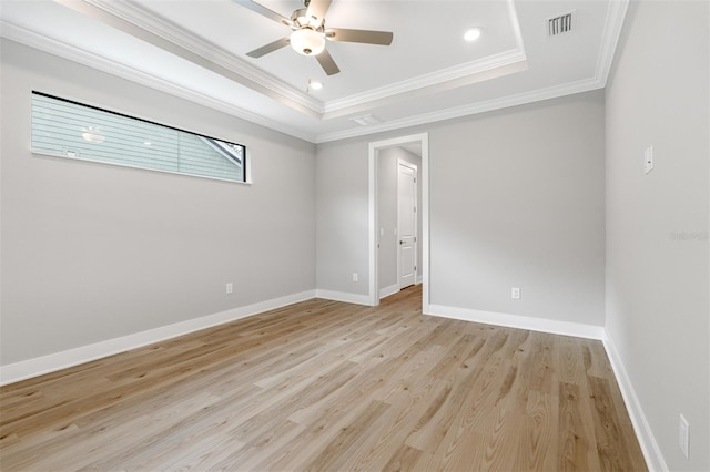 spare room featuring ornamental molding, a tray ceiling, light wood-type flooring, and ceiling fan