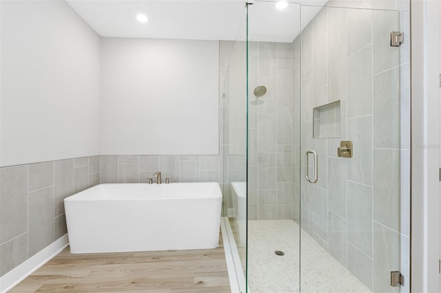 bathroom with tile walls, hardwood / wood-style flooring, and independent shower and bath