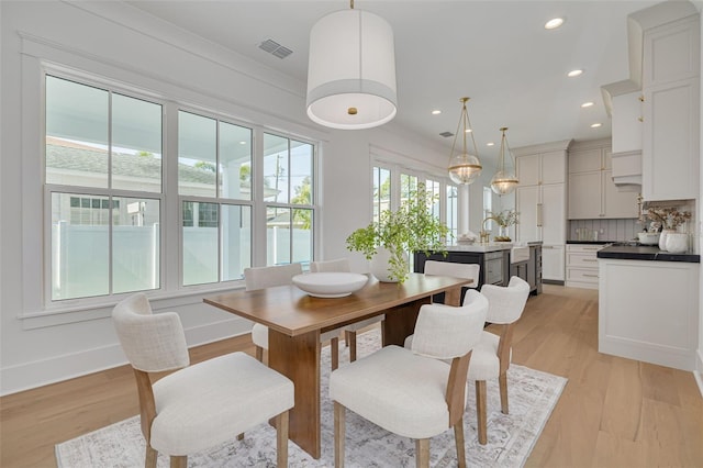 dining space featuring crown molding and light hardwood / wood-style floors