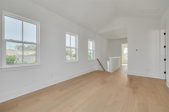 spare room featuring lofted ceiling and light wood-type flooring