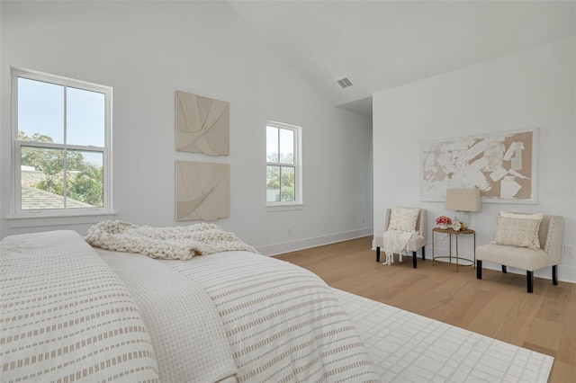 bedroom with high vaulted ceiling, multiple windows, and light wood-type flooring