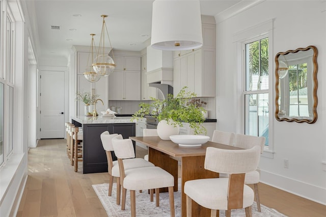 dining area featuring ornamental molding, an inviting chandelier, and light hardwood / wood-style floors