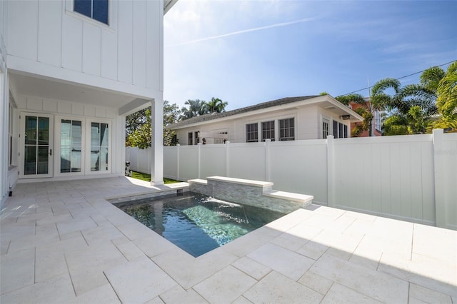 view of swimming pool featuring a patio, pool water feature, and french doors