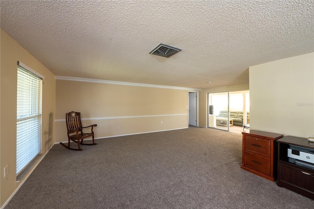 unfurnished room with a textured ceiling, dark colored carpet, visible vents, and a healthy amount of sunlight