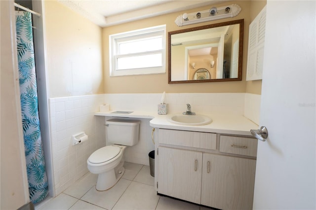 full bath featuring toilet, vanity, tile walls, wainscoting, and tile patterned floors