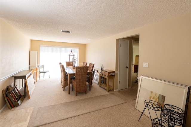 carpeted dining space with a textured ceiling and visible vents